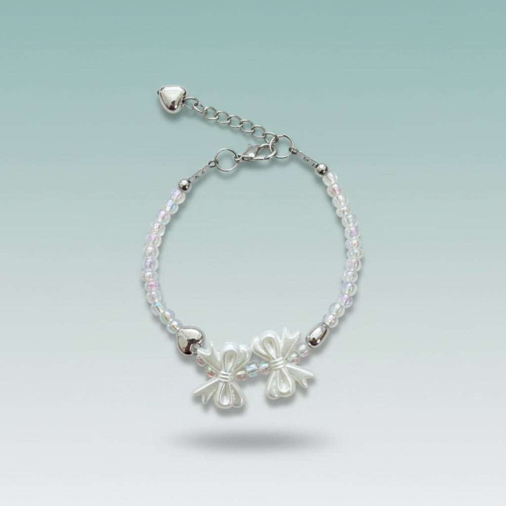Silver-toned beaded bracelet featuring two delicate bow charms, translucent crystal-like beads, and an adjustable chain with small heart details.