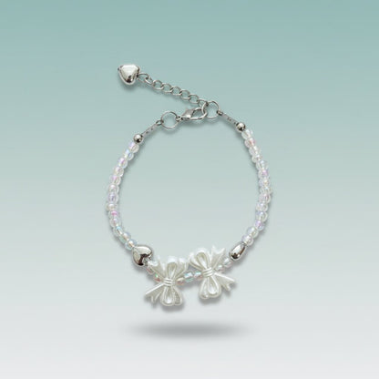 Silver-toned beaded bracelet featuring two delicate bow charms, translucent crystal-like beads, and an adjustable chain with small heart details.