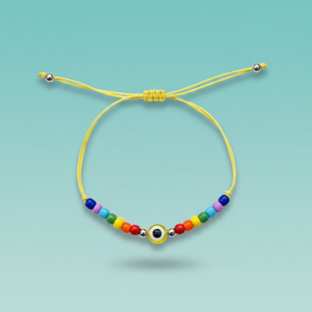 An adjustable yellow string bracelet featuring a central yellow and white evil eye charm, accented by small silver beads and a vibrant sequence of multi-colored beads on a light teal background.