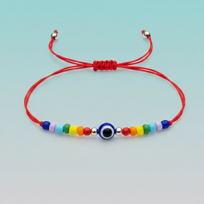 An adjustable red string bracelet featuring a central blue and white evil eye charm, accented by small silver beads and a colorful sequence of multi-colored beads on a light blue background.