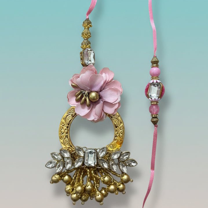 Gifthubmart Gulab Ghunghru BB Rakhi with pink flower pendant and crystal-studded gold accents.
