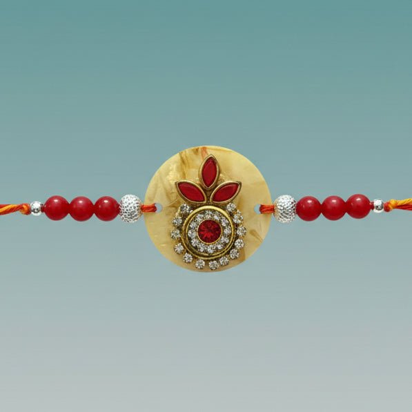 Ivory Moli Rakhi by Gifthubmart with red beads and a gold centerpiece