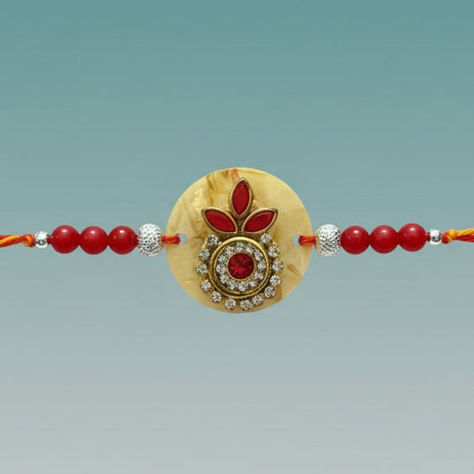 Ivory Moli Rakhi by Gifthubmart with red beads and a gold centerpiece