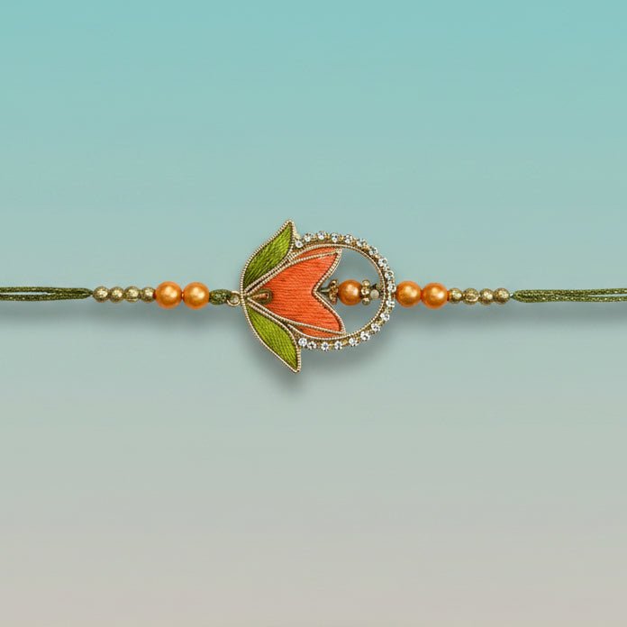 Kashida Rakhi by Gifthubmart, orange bead centerpiece with crystal halo on green cord.
