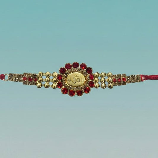 Om Rakhi 100B by Gifthubmart – red gemstone centerpiece with gold beads on red thread