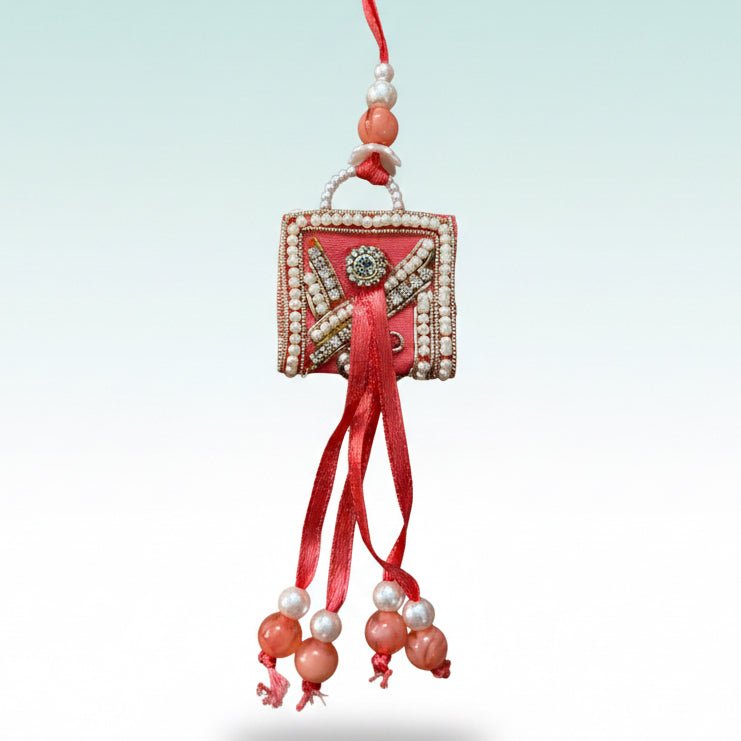 Peach Purse BB Rakhi with red thread and pearl-embellished pendant by Gifthubmart