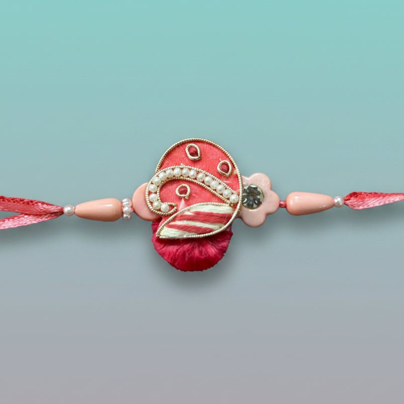 Peach Purse BB Rakhi by Gifthubmart on pink thread with pearl accents.