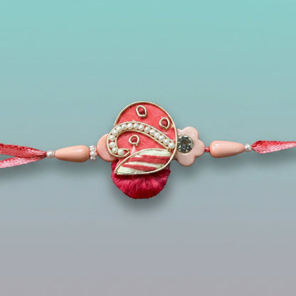 Peach Purse BB Rakhi by Gifthubmart on pink thread with pearl accents.