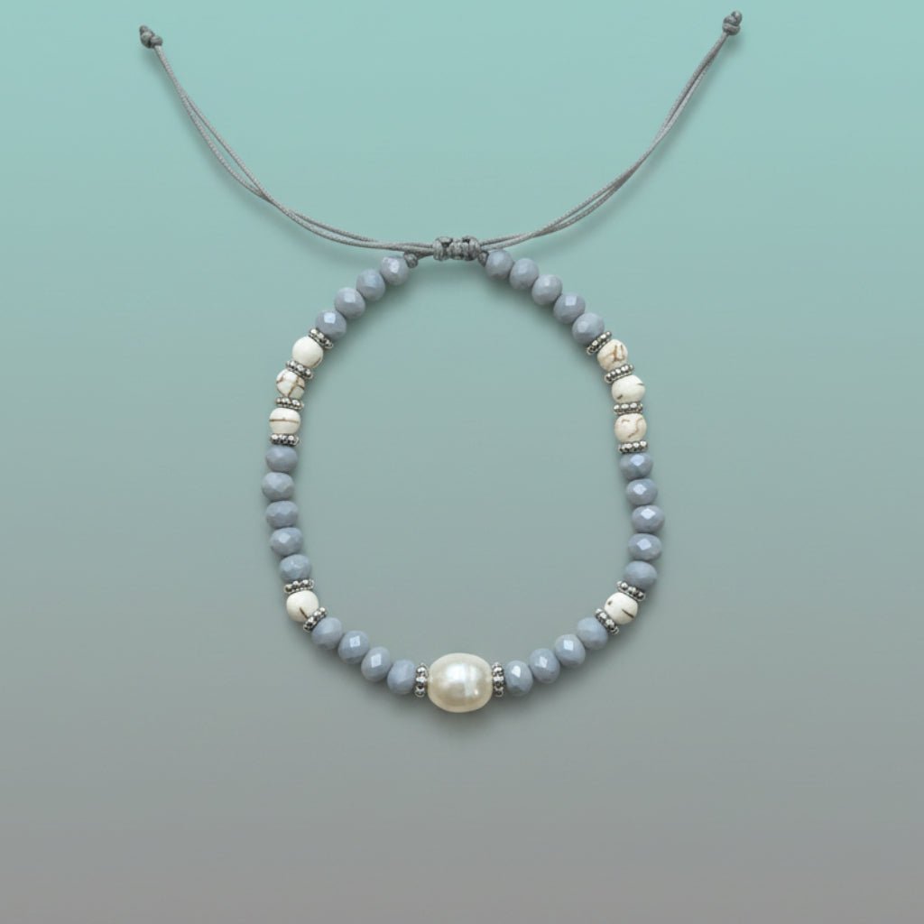 Delicate handmade adjustable string bracelet featuring a large central white pearl, accented by smaller light blue and marbled white beads with silver spacers on a soft mint green background.