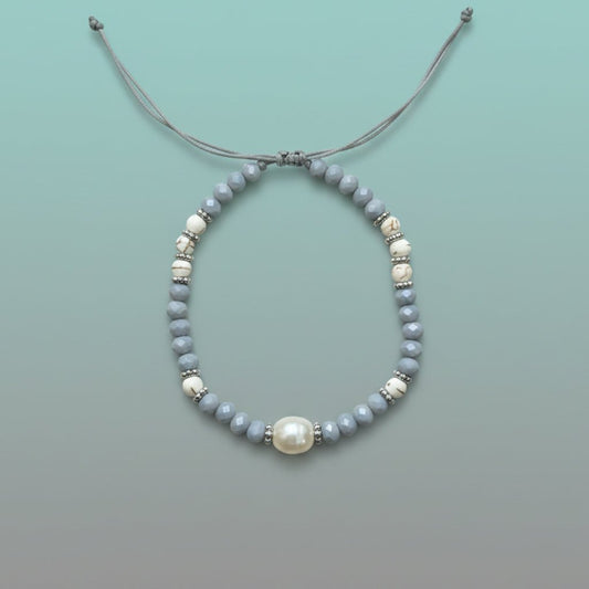 Delicate handmade adjustable string bracelet featuring a large central white pearl, accented by smaller light blue and marbled white beads with silver spacers on a soft mint green background.