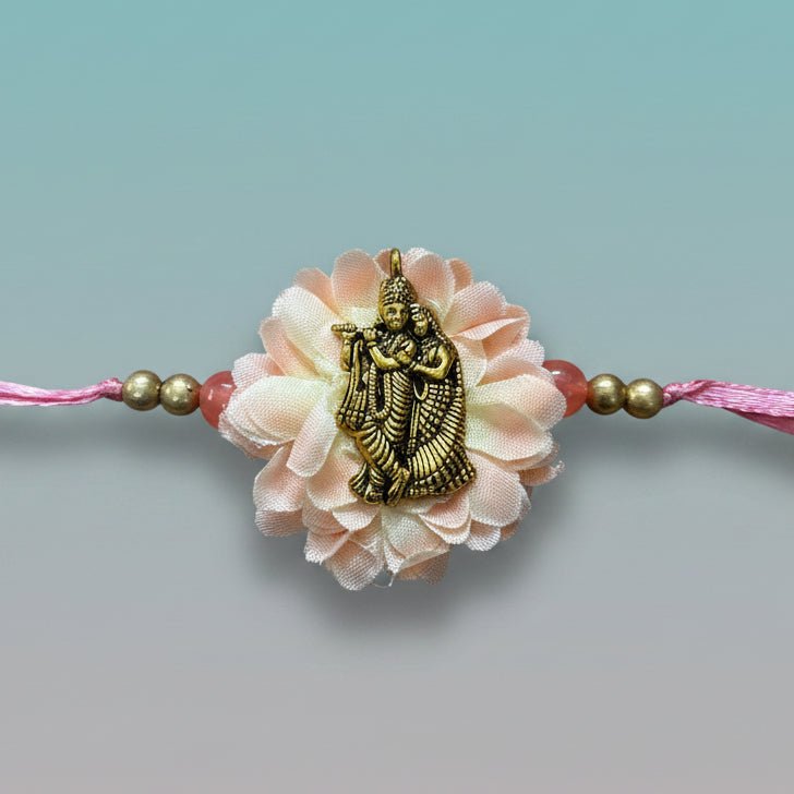 Radha Krishna Bb Rakhi by Gifthubmart, pink beaded bracelet with golden pendant and flower centerpiece