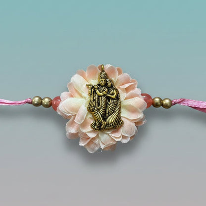 Radha Krishna Bb Rakhi by Gifthubmart, pink beaded bracelet with golden pendant and flower centerpiece