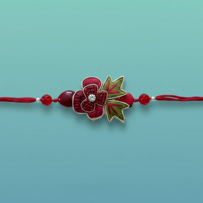 Gifthubmart Rose Bb Rakhi with red flower charm, crystal centerpiece and green leaf accents.